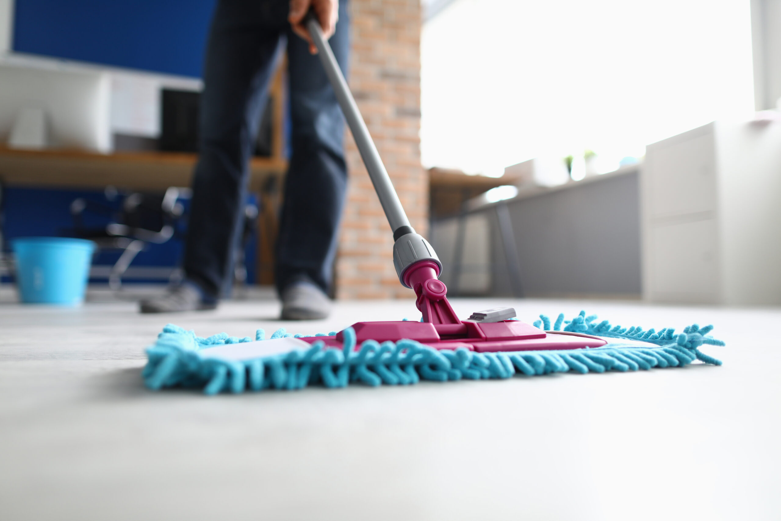Man with mop washes floor in office closeup